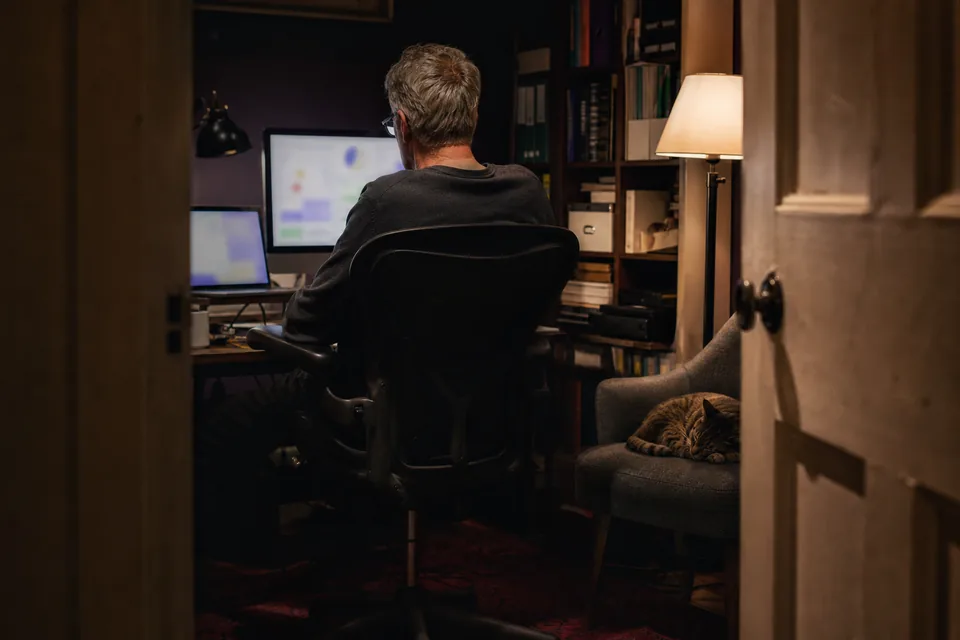 A site owner reading his blog statistics on a monitor in a dim home office